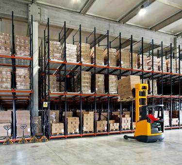 Forklift placing product on a rack in a warehouse Forklift placing product on a rack in a warehouse